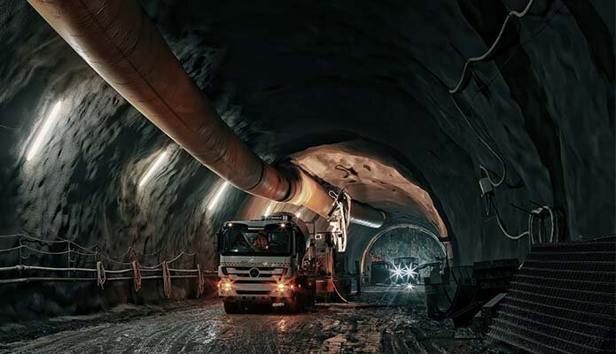 Das Bild zeigt ein Baustellenfahrzeug im Bergbau, das sich in einem Tunnel befindet. Die Aufnahme ist relativ dunkel gehalten, wodurch die Atmosphäre der unterirdischen Arbeitsumgebung betont wird.