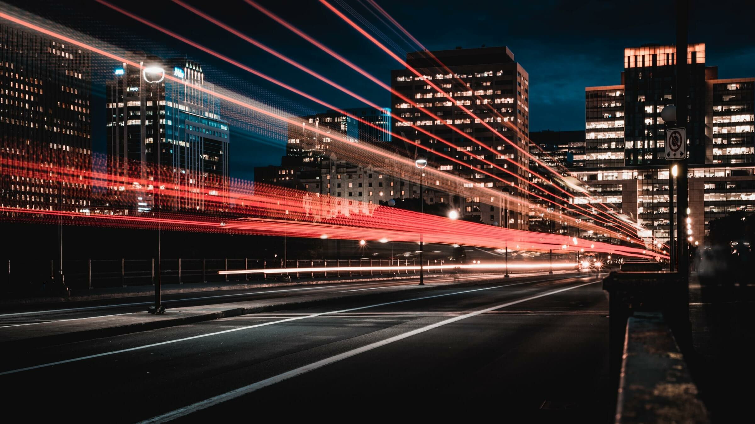 Eine Stadt bei Nacht mit imposantem Lichtspiel. Die Lichter der Fahrzeuge als Streifen in Rot- und Gelbtönnen sichtbar