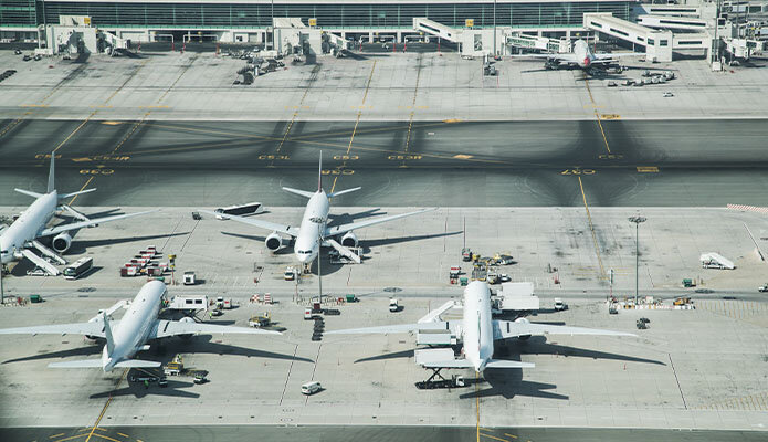 Das Bild zeigt vier Transportflugzeuge, die an einem Flughafen versetzt gegenüber geparkt sind. Es handelt sich hierbei nicht um Passagierflugzeuge, sondern um Flugzeuge, die speziell für den Transport von Fracht und Gütern ausgelegt sind.